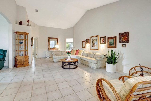 living room featuring light tile patterned floors, visible vents, arched walkways, and high vaulted ceiling