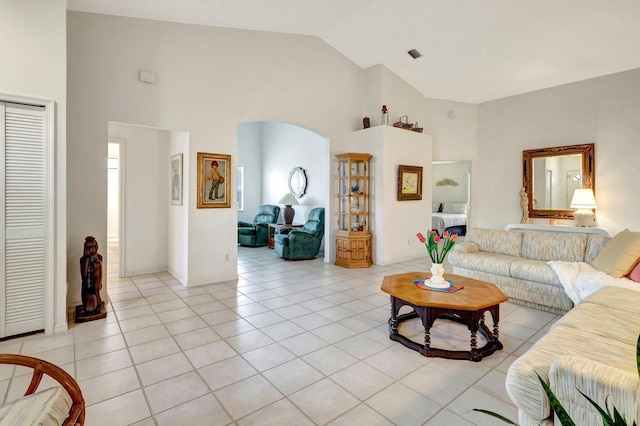 living room featuring light tile patterned floors, visible vents, arched walkways, and high vaulted ceiling