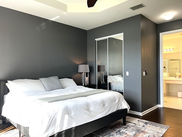 bedroom featuring hardwood / wood-style floors, connected bathroom, ceiling fan, and a closet