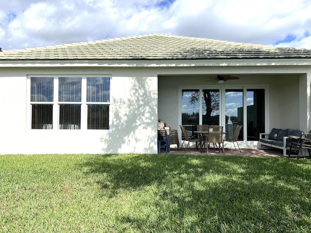 rear view of house featuring ceiling fan, outdoor lounge area, a patio area, and a lawn