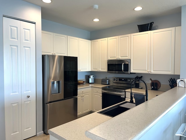 kitchen featuring white cabinetry, appliances with stainless steel finishes, and kitchen peninsula