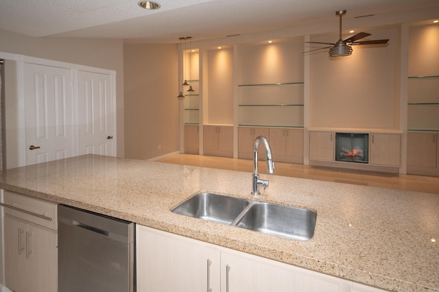 kitchen with white cabinetry, sink, stainless steel dishwasher, and light stone counters