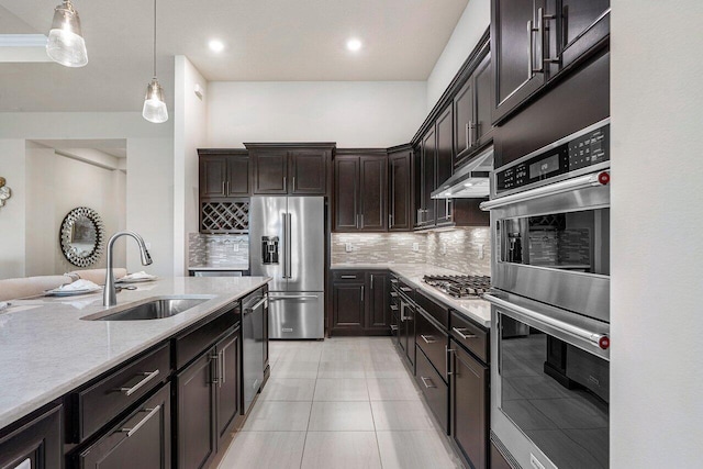 kitchen with sink, stainless steel appliances, tasteful backsplash, dark brown cabinetry, and decorative light fixtures