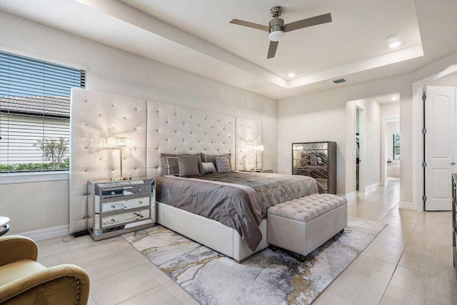 bedroom featuring light tile patterned floors, a tray ceiling, and ceiling fan