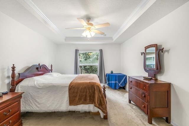 bedroom with ceiling fan, a tray ceiling, ornamental molding, a textured ceiling, and light carpet