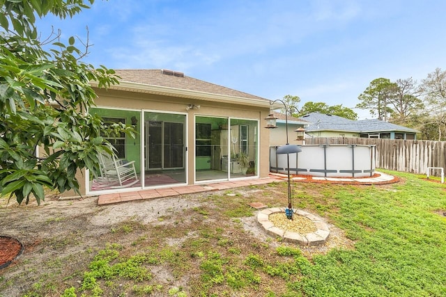 rear view of property featuring a yard and a fenced in pool