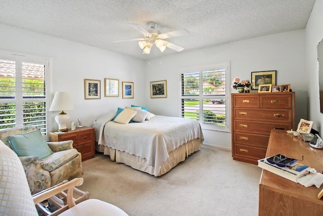 bedroom with multiple windows, ceiling fan, light carpet, and a textured ceiling