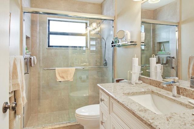 bathroom featuring vanity, a shower with shower door, and toilet