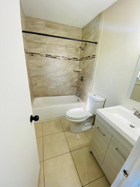 full bathroom featuring tile patterned floors, toilet, tiled shower / bath combo, and vanity