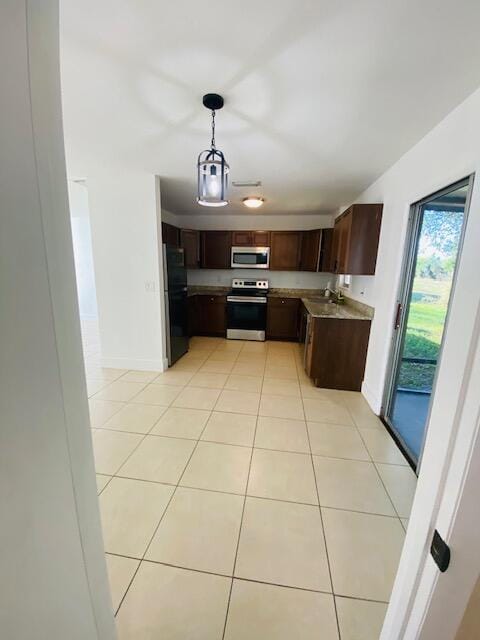 kitchen featuring light tile patterned floors, sink, appliances with stainless steel finishes, hanging light fixtures, and dark brown cabinets