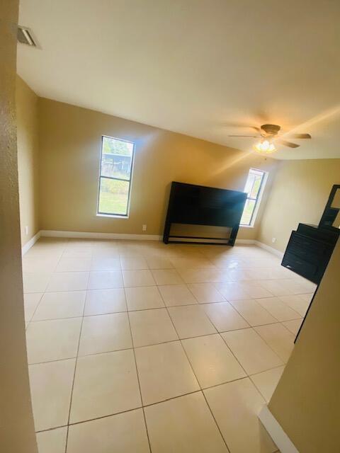 unfurnished living room with light tile patterned flooring and ceiling fan