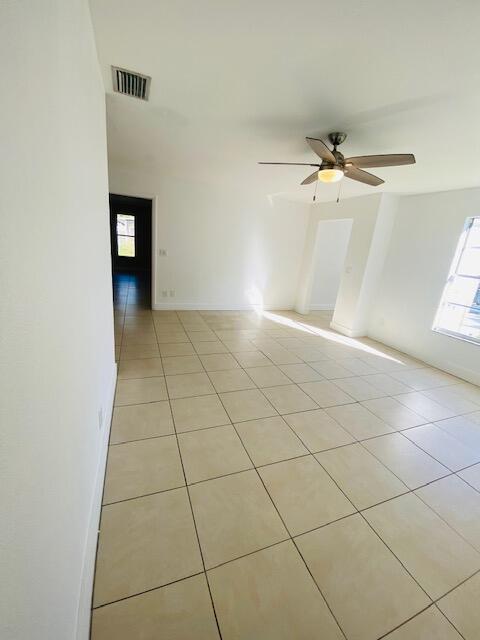 tiled spare room with ceiling fan