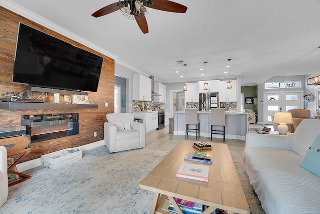 living room with french doors, crown molding, ceiling fan, and wood walls