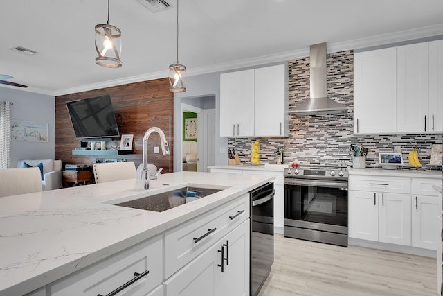 kitchen featuring wall chimney range hood, sink, white cabinetry, hanging light fixtures, and stainless steel electric stove