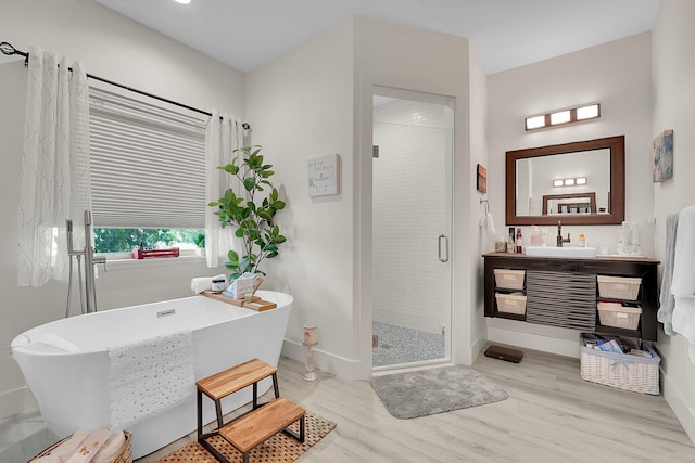 bathroom with hardwood / wood-style flooring, plus walk in shower, and vanity