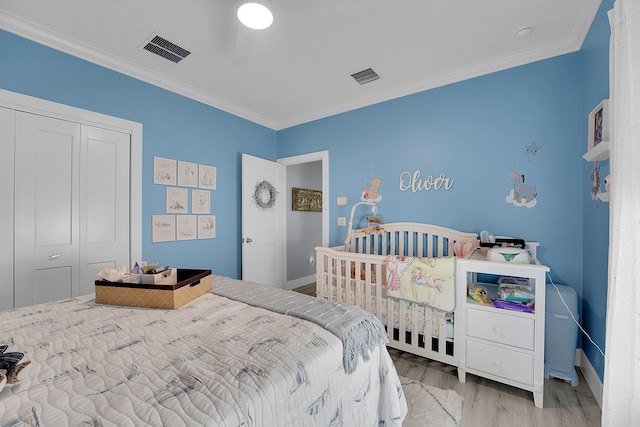 bedroom featuring crown molding, light hardwood / wood-style flooring, and a closet