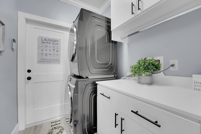 laundry room with crown molding, cabinets, stacked washer and clothes dryer, and light wood-type flooring