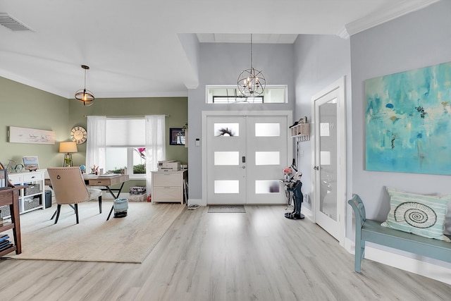 entrance foyer with french doors, ornamental molding, an inviting chandelier, and light hardwood / wood-style floors