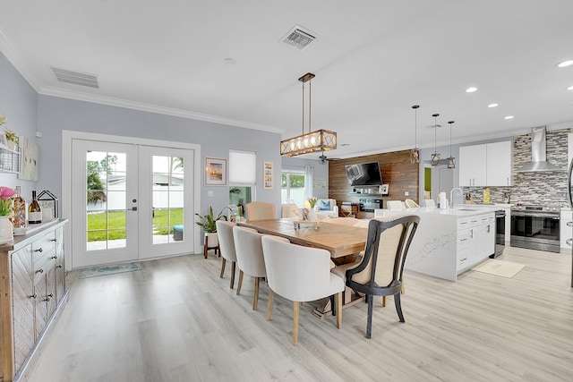 dining room featuring a wealth of natural light, sink, light hardwood / wood-style flooring, ornamental molding, and french doors