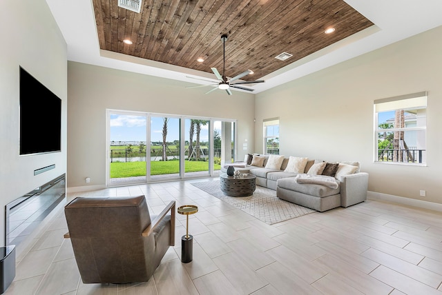 living room with wooden ceiling, ceiling fan, and a tray ceiling