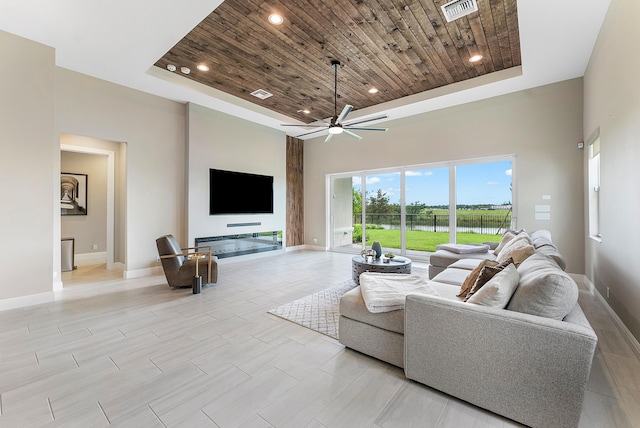 living room with a raised ceiling, a towering ceiling, wooden ceiling, and ceiling fan