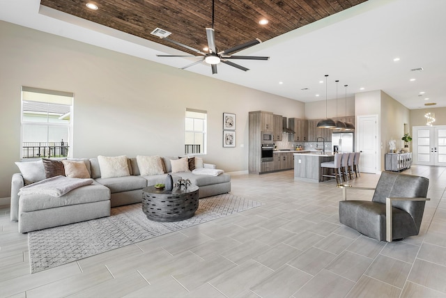 tiled living room featuring ceiling fan, plenty of natural light, sink, and wood ceiling