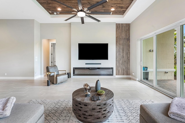 living room featuring a tray ceiling, wooden ceiling, and ceiling fan