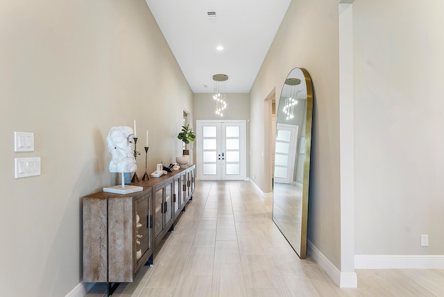 hallway featuring an inviting chandelier and french doors