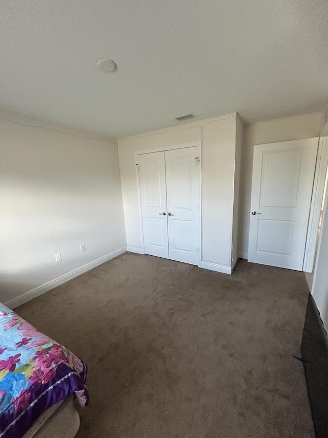 unfurnished bedroom with dark colored carpet and a closet