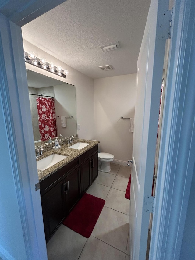 bathroom with vanity, walk in shower, toilet, tile patterned floors, and a textured ceiling