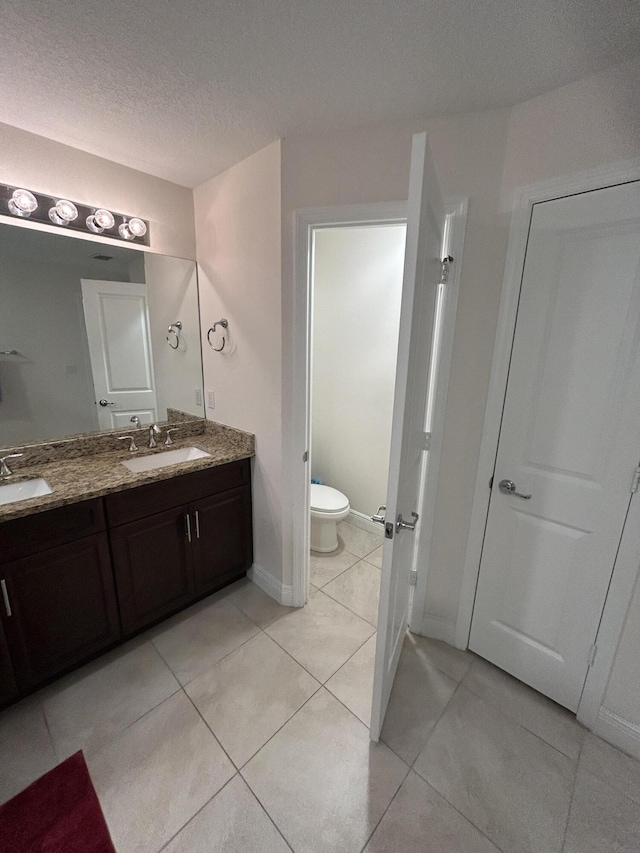 bathroom featuring vanity, toilet, tile patterned flooring, and a textured ceiling