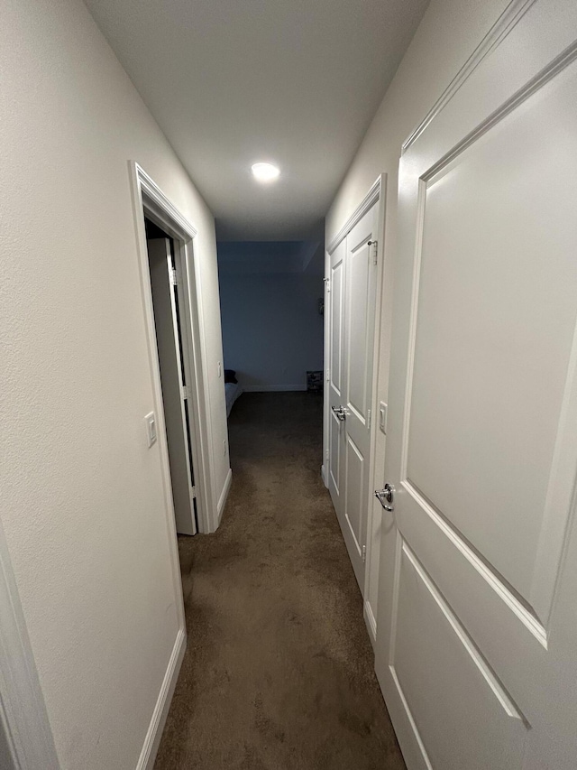 hall featuring dark colored carpet