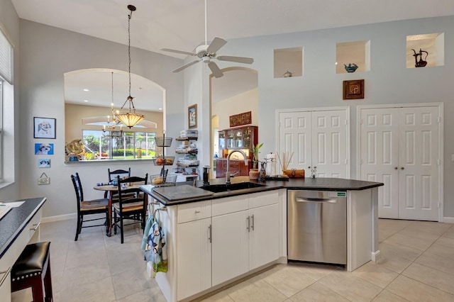 kitchen with sink, light tile patterned floors, white cabinets, decorative light fixtures, and stainless steel dishwasher