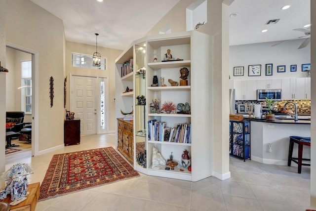 foyer entrance with sink, ceiling fan with notable chandelier, and light tile patterned flooring