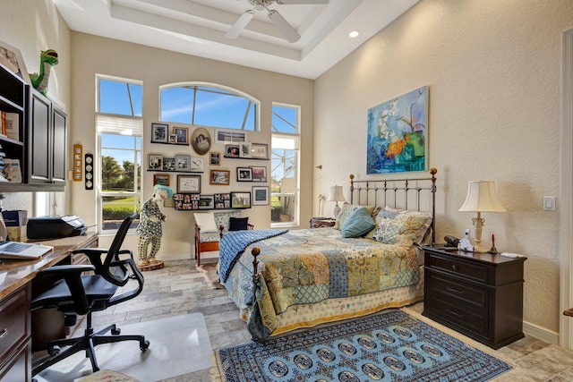 bedroom with a tray ceiling, ceiling fan, and a high ceiling