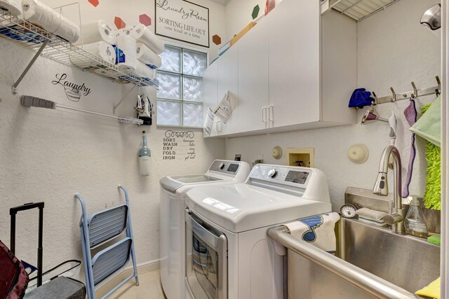 washroom with cabinets, washer and dryer, and sink