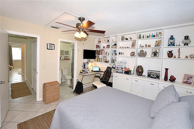 bedroom featuring ceiling fan, ensuite bath, a textured ceiling, and light tile patterned floors