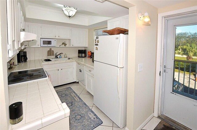 kitchen featuring sink, light tile patterned floors, tile counters, white appliances, and white cabinets