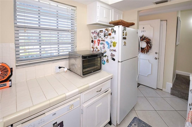 kitchen featuring tile countertops, white cabinets, white appliances, and light tile patterned floors