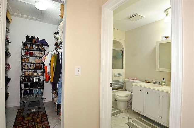 bathroom featuring tile patterned flooring, vanity, a textured ceiling, and toilet