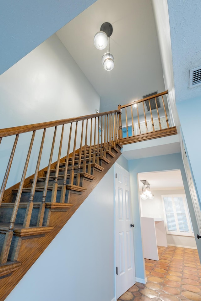 stairs with tile patterned floors and high vaulted ceiling