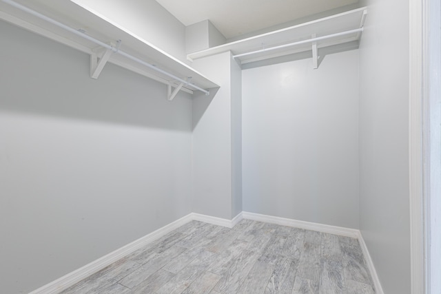 walk in closet with light hardwood / wood-style floors