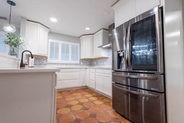 kitchen with stainless steel refrigerator, white cabinetry, wall chimney exhaust hood, and tasteful backsplash