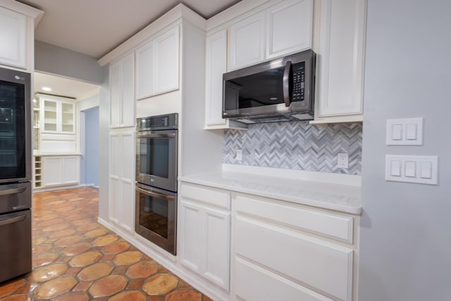 kitchen with white cabinetry, appliances with stainless steel finishes, and backsplash