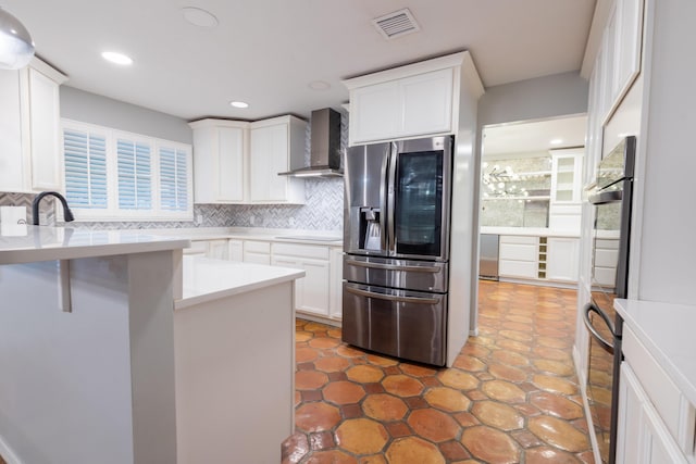 kitchen with appliances with stainless steel finishes, tasteful backsplash, sink, white cabinets, and wall chimney range hood