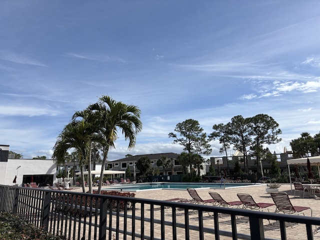 community pool featuring a residential view, fence, and a patio