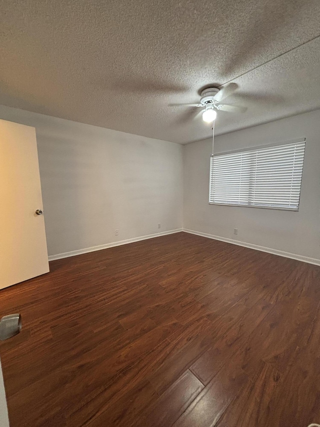 unfurnished room with dark wood-style flooring, ceiling fan, a textured ceiling, and baseboards