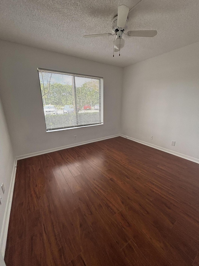 empty room featuring dark wood-style floors, ceiling fan, a textured ceiling, and baseboards