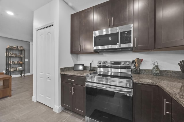 1316 SW Abacus Ave, Port Saint Lucie, FL 34953 - kitchen with stainless steel appliances, dark brown cabinets, baseboards, dark stone countertops, and recessed lighting
