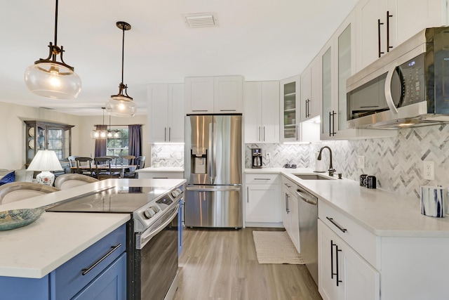 kitchen featuring appliances with stainless steel finishes, sink, hanging light fixtures, and white cabinets